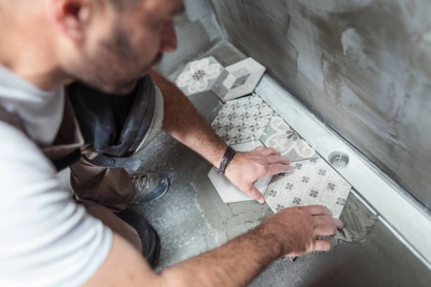 person applying tiles in bathroom -bathroom tile