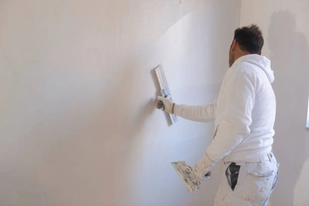 person with white hoodie painting white wall -sheetrock vs drywall