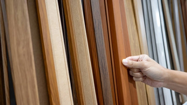 Hand selecting various wooden laminate samples in a display rack. -carpentry contractors