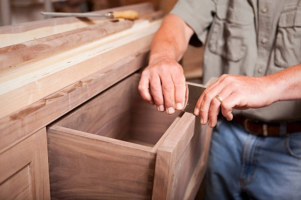 A carpenter carefully assembling a wooden drawer for cabinetry. -custom carpentry