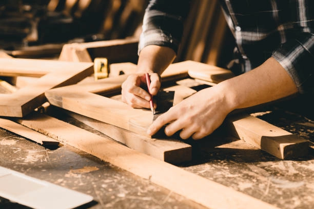 Woodworker measuring and marking wooden pieces for a precise cut. -rough carpentry