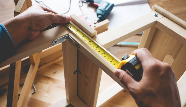 Person using a tape measure to check wooden frame dimensions. -rough carpentry