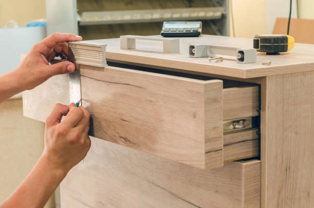 Person installing a handle on a wooden drawer with precision. -rough carpentry