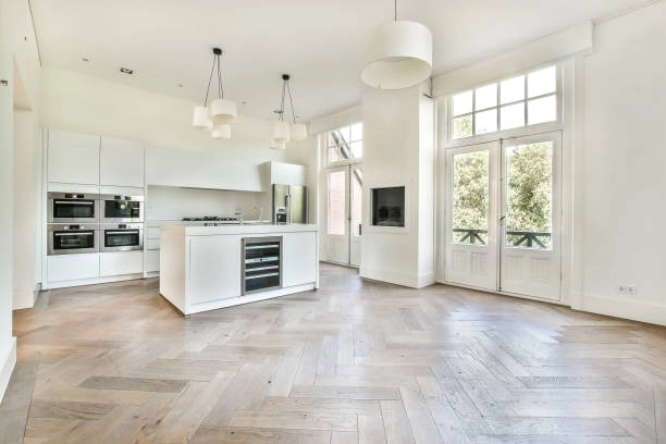 Bright modern kitchen with white cabinetry, large windows, and herringbone floors. -kitchen remodel contractor