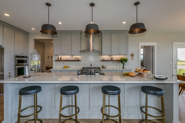 Modern kitchen with large island, pendant lighting, and sleek gray cabinets. -kitchen remodels before and after