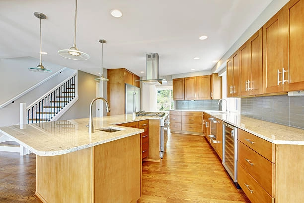 Spacious kitchen with light wood cabinets, marble countertops, and two islands. -kitchen remodels before and after