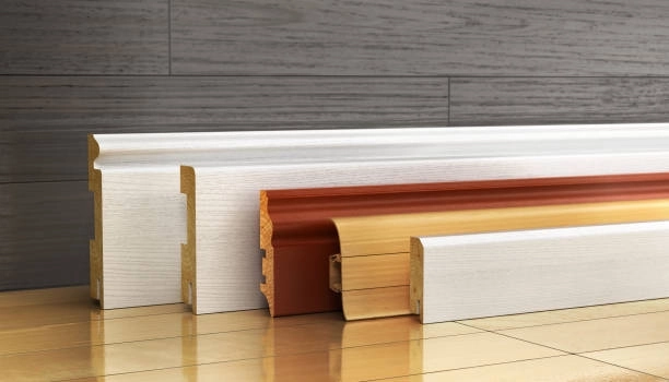 Various wooden baseboards in different colors and styles on floor. -finish trim carpentry